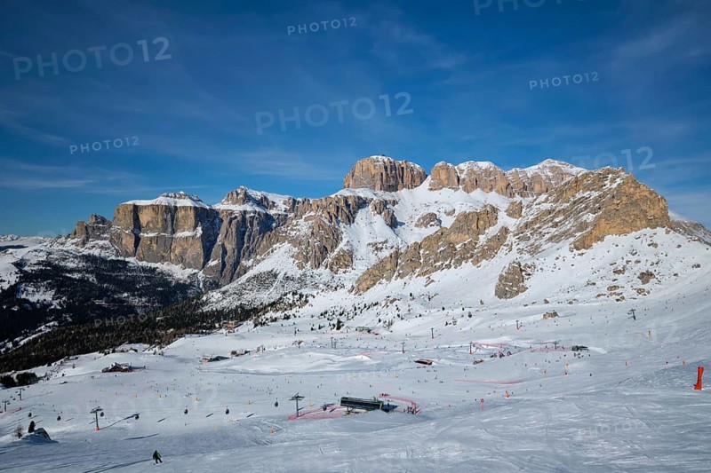View of a ski resort piste with people skiing in Dolomites in Italy. Ski area Belvedere. Canazei