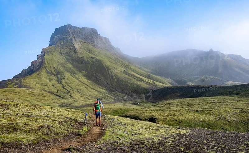 Hikers on trail through moss-covered mountain landscape