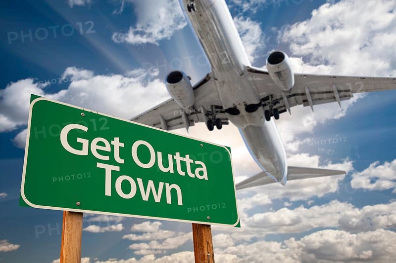 Get outta town green road sign against dramatic clouds and sky