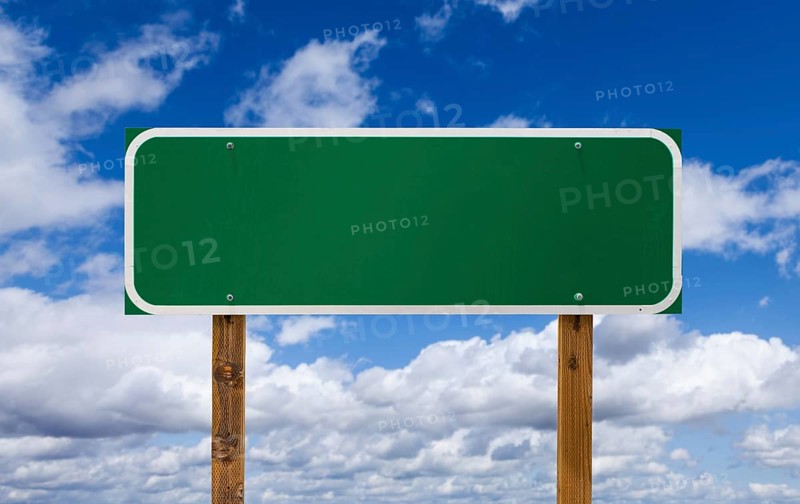 Blank green road sign with wooden posts over blue sky and clouds