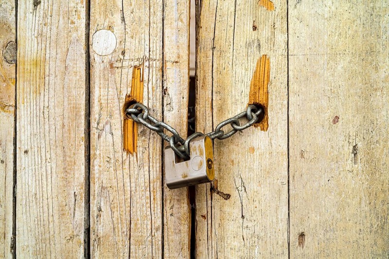 Rusty padlock locking old wooden door with a chain
