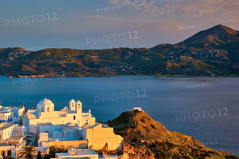 View of Plaka village on Milos island with traditional greek white houses with Greek Orthodox christian churck on sunset. Plaka town