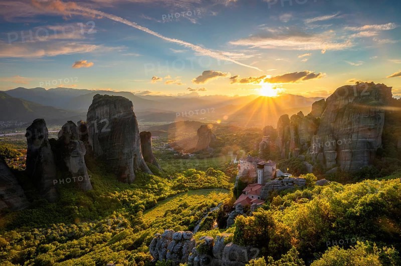 Sunset over monastery of Rousanou and Monastery of St. Nicholas Anapavsa in famous greek tourist destination Meteora in Greece on sunset with sun rays and lens flare
