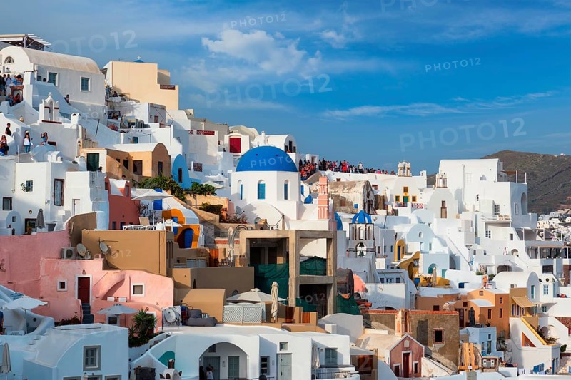 Tourist crowd and queue to a famous viewpoint with greek orthodox church blue dome in Oia Village