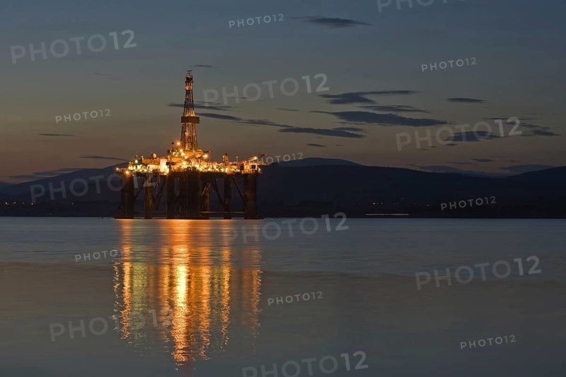Oil rig moored in sea near coast at night