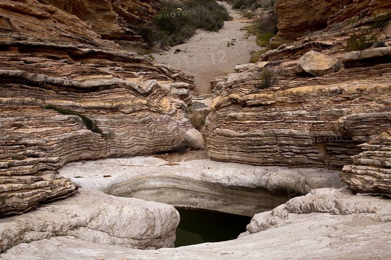 Rock strata and canyon with water in eroded depression on bedrock