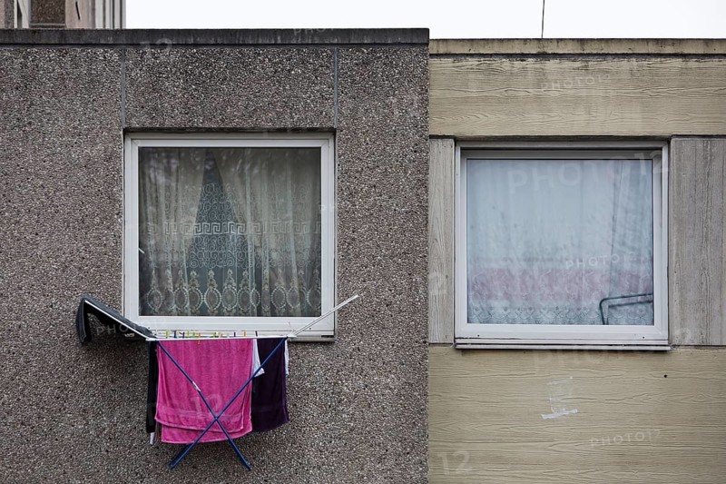 Laundry rack hanging out of the window on the first floor of a dreary apartment block