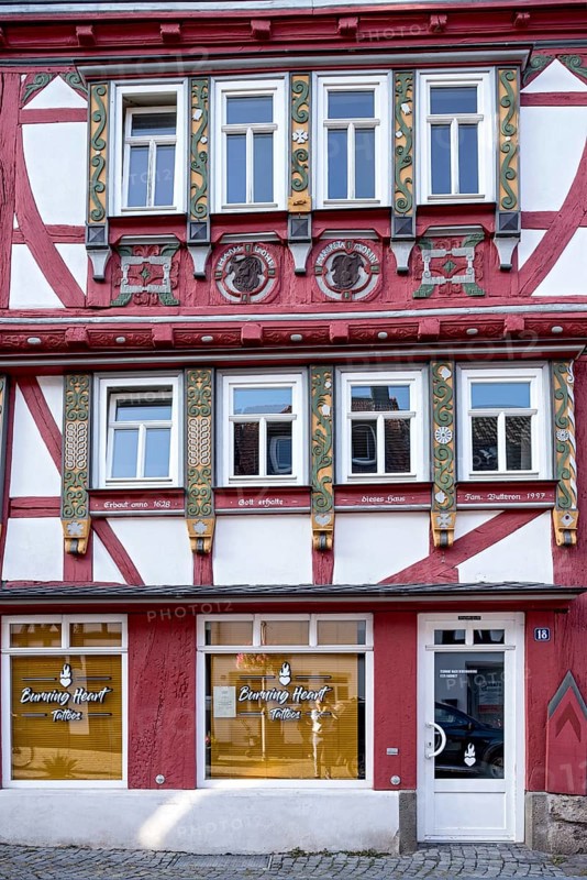 Historic half-timbered house with colourfully painted and carved wooden beams and family coat of arms