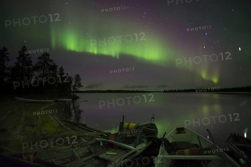 Aurora and stars over the lake with stranded canoes at night