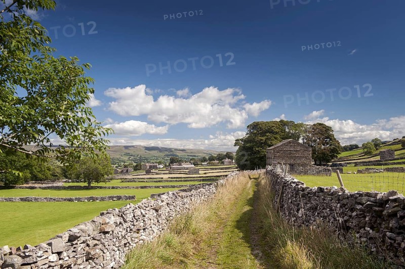 Lane in farmland with dry stone walls and stone barns