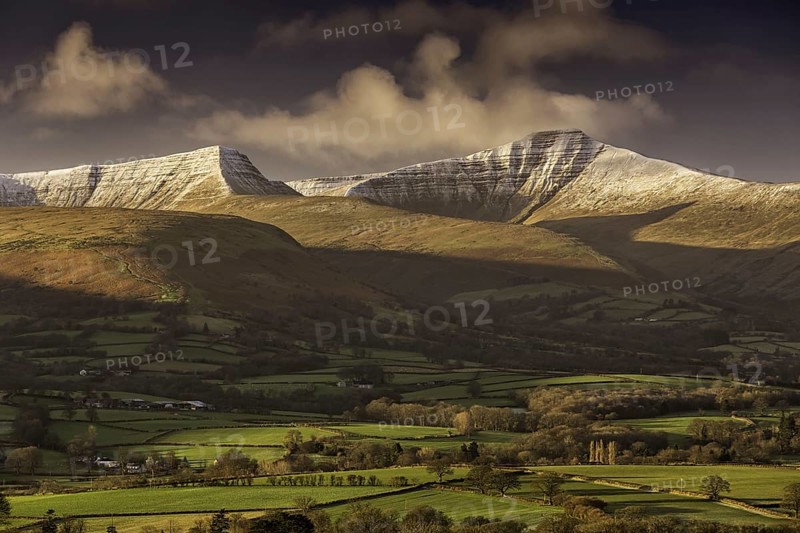 View of farmland and snow-capped hills at sunrise