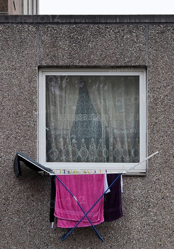 Laundry rack hanging out of the window on the first floor of a dreary apartment block