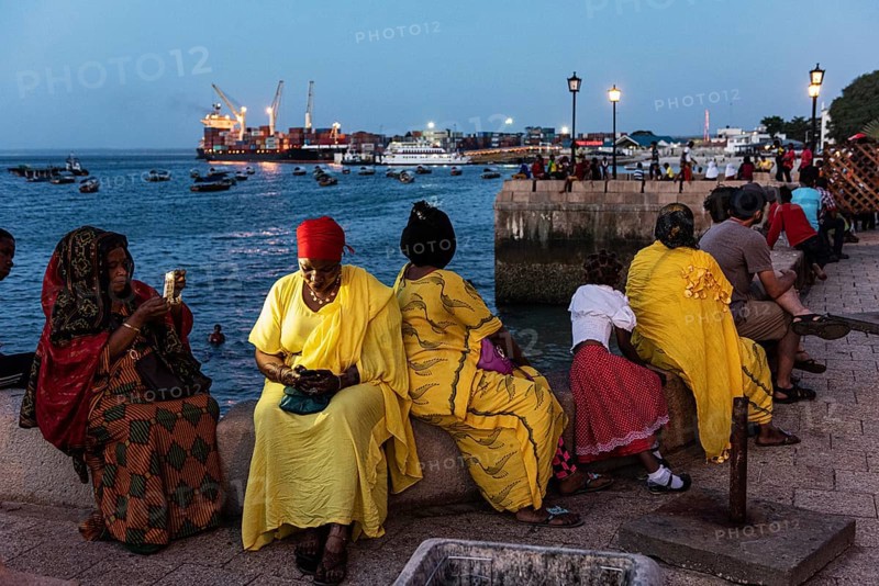 Frauen in bunten Tuechern sitzen an der Promenade des Fodharani Park