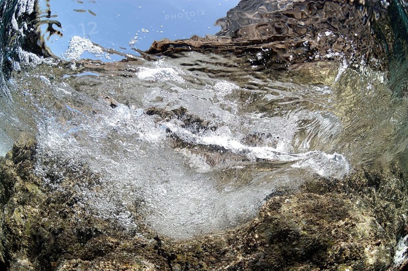 Wave breaking on rocky ledge underwater