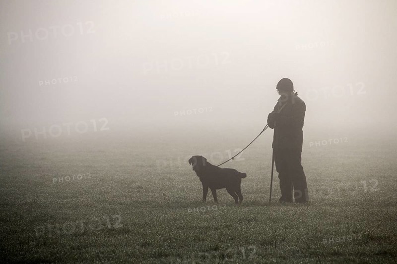 Picker stands in the field with trained dog waiting for pheasant shooting to begin