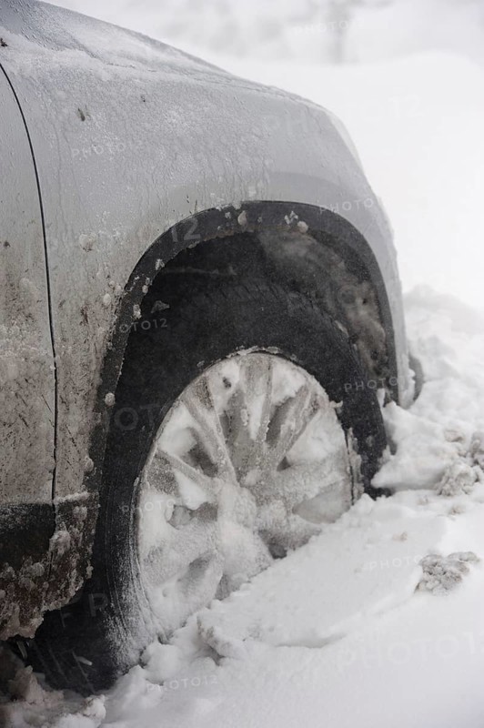 Close-up of a car wheel stuck in a snowdrift after a blizzard