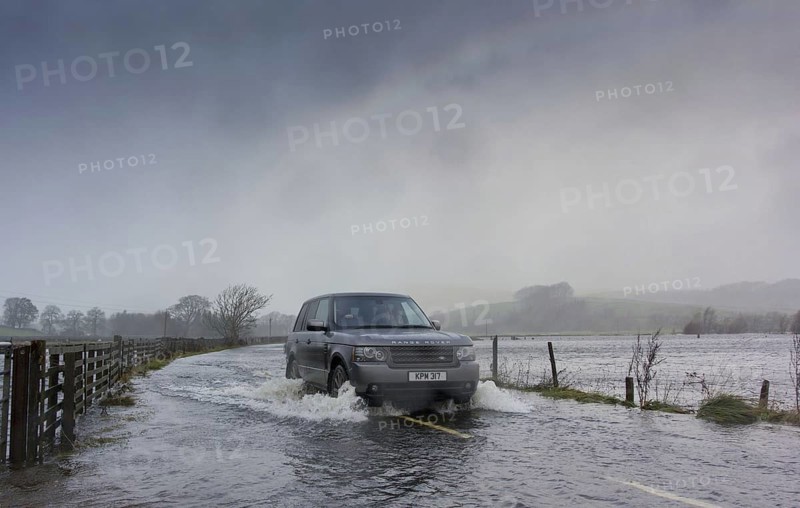 Range Rover driving on road flooded during heavy rain