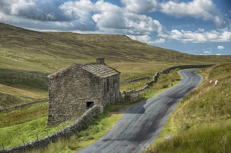 View of dry stone walls and stone barn beside the road