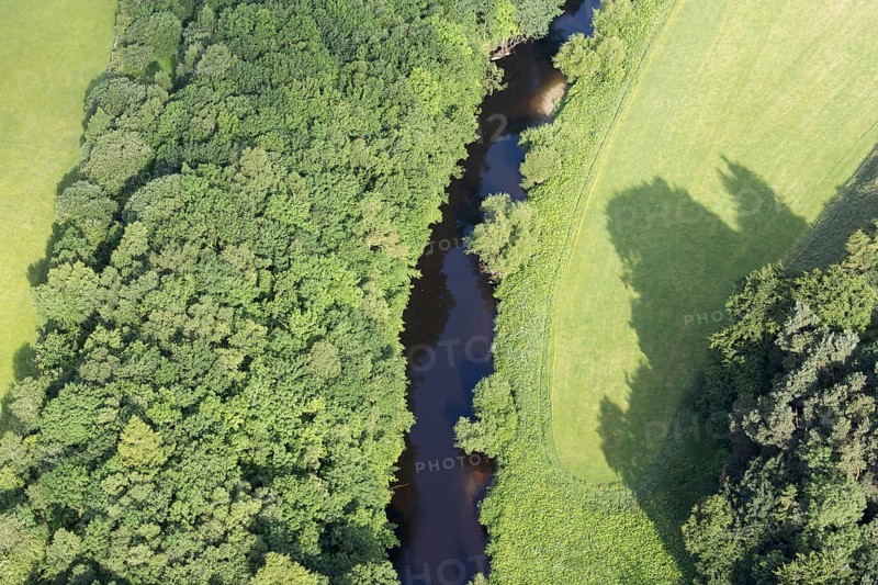 Aerial view of a river surrounded by woodland and flowing through farmland