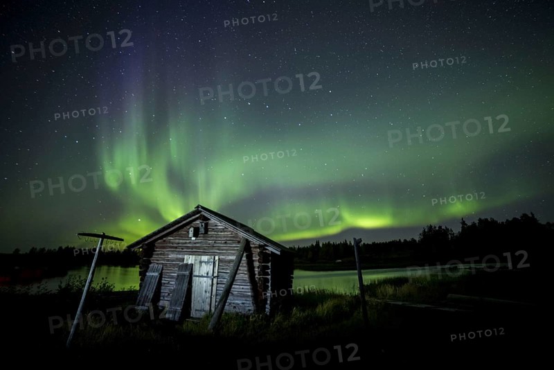 Aurora Borealis and stars over fishing hut and lake at night
