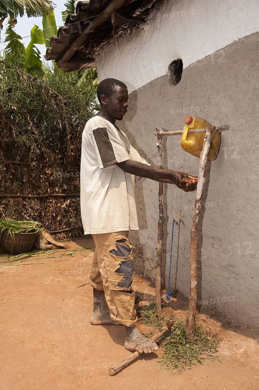 Man washes hands under self-made water tap from plastic container