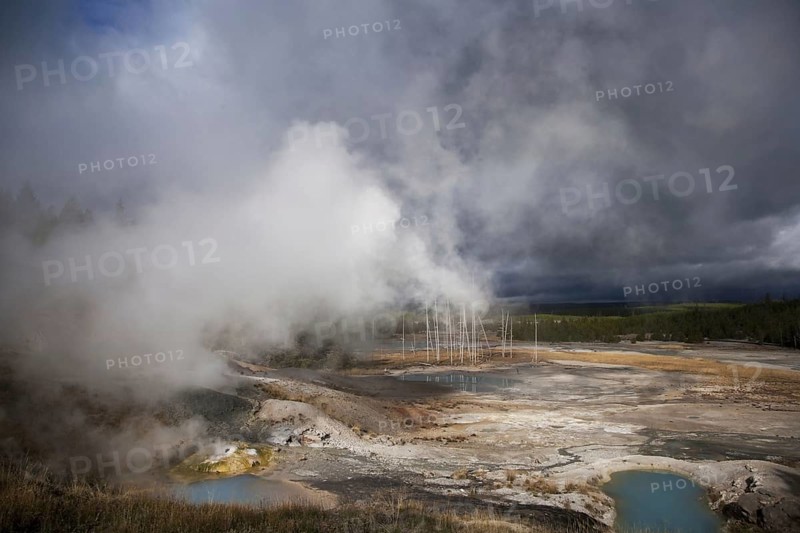 View of hot springs with steam and approaching storm clouds