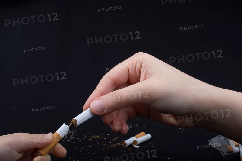 Hand is breaking a cigarette on a black background