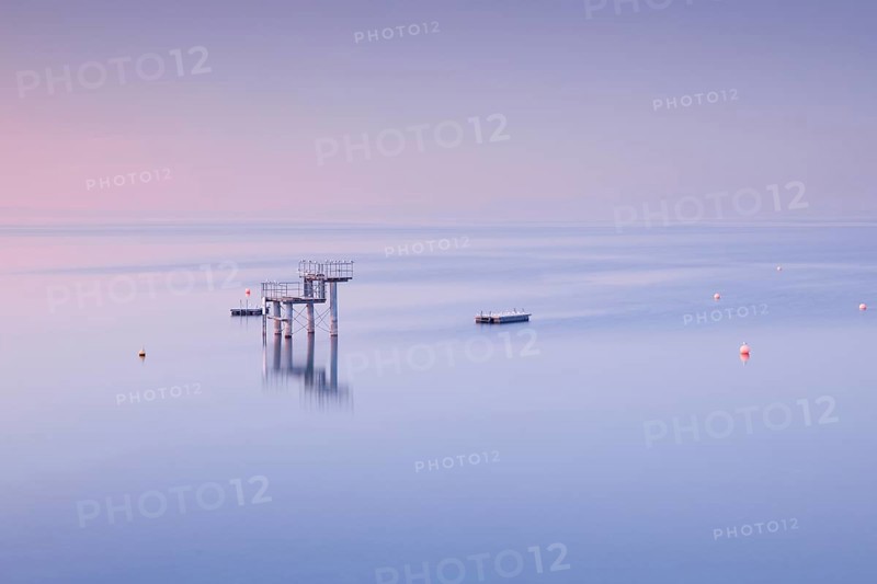 Rosa-violette Abendstimmung ueber dem Bodensee mit Blick zum Sprungturm und den Flossen der Freibadanlage Horn inmitten des Sees
