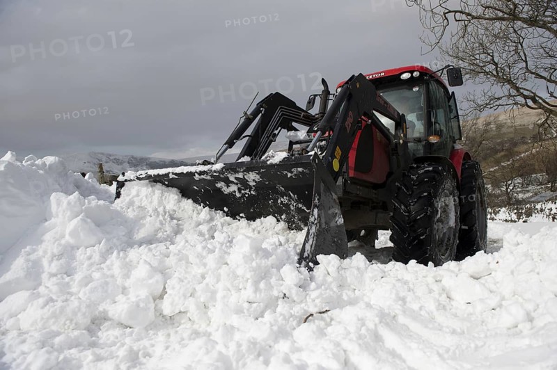 Zetor tractor with loader clears snow from blocked country road after snowstorm