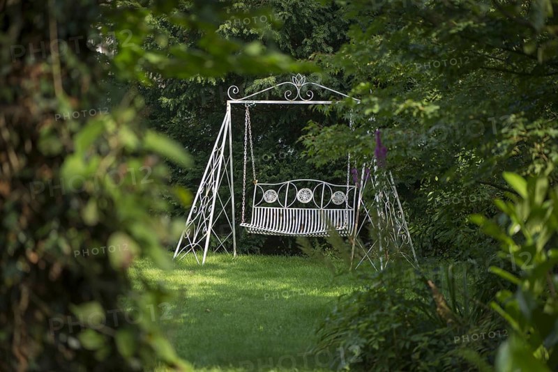 Swinging garden seat on lawn in garden