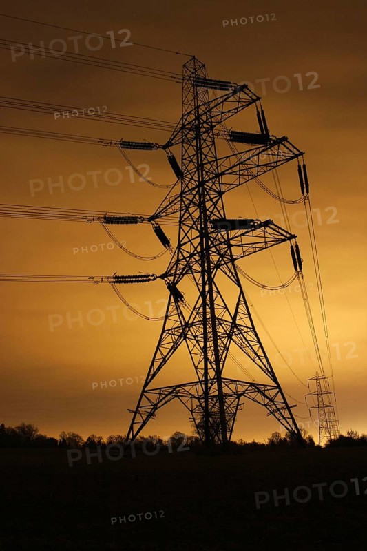 Electricity pylon and overhead power lines illuminated at night by light pollution in the city of Leicester