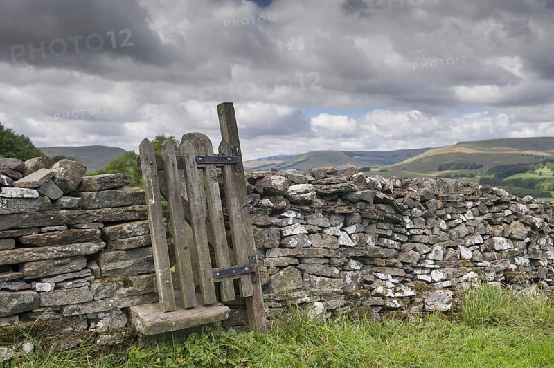 Stiles and gate in dry stone wall on public footpath