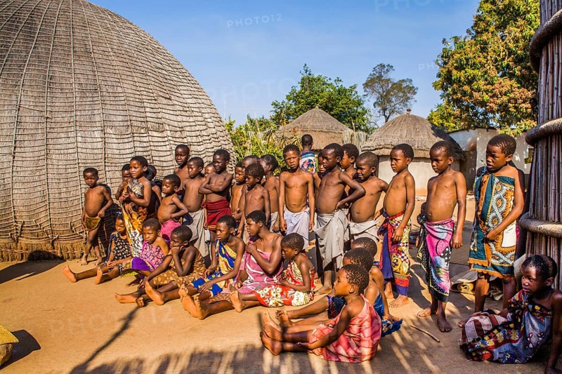 Children watch with interest at traditional customs in real African village