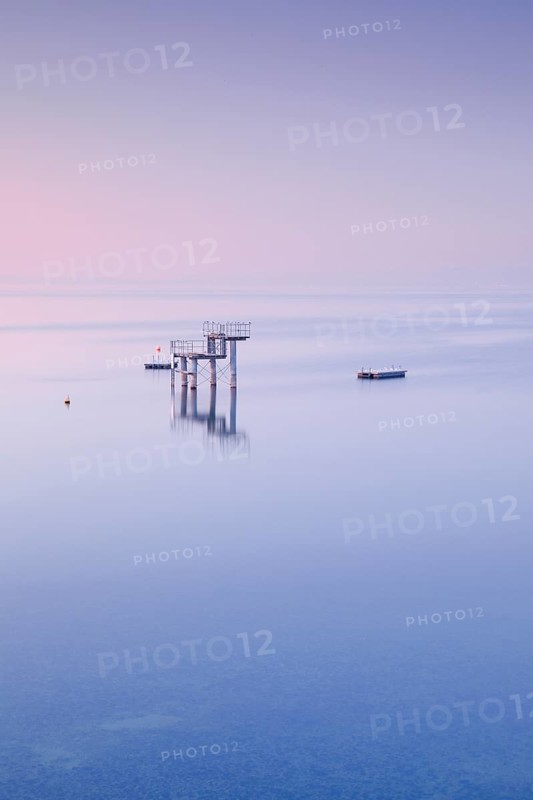 Rosa-violette Abendstimmung ueber dem Bodensee mit Blick zum Sprungturm und den Flossen der Freibadanlage Horn inmitten des Sees
