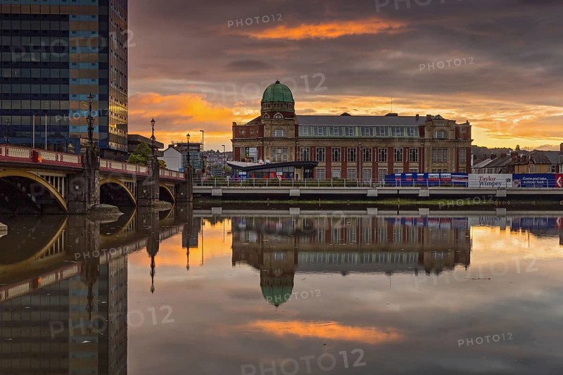 Refurbished dwelling with copper dome reflected in the river at sunrise