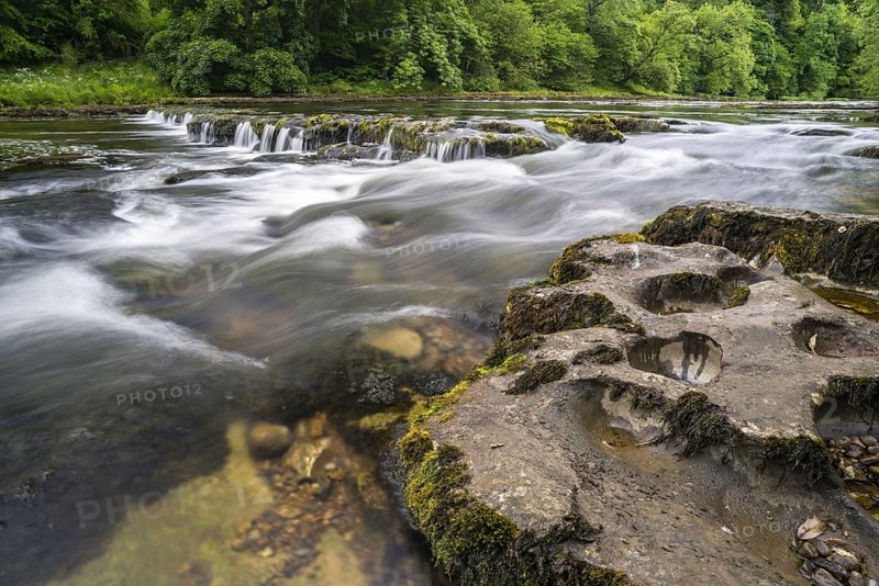 View of eroded rocks beside river and waterfall
