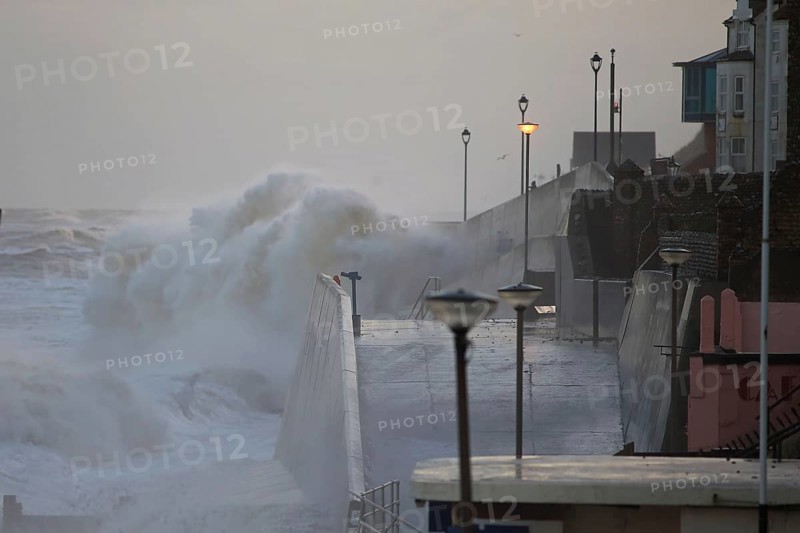 Waves crashing against the seawall of the coastal town during the tidal surge