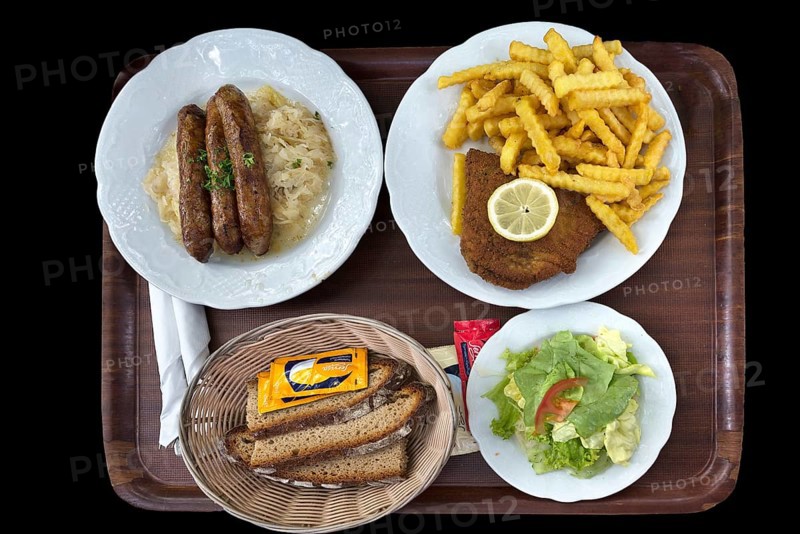 Bratwurst with sauerkraut and bread and cordon bleu with french fries on a tray on a black background