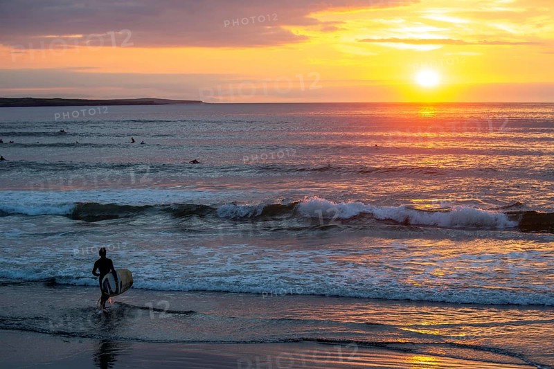 Man with surfboard rushing into water at Strandhill. Sligo