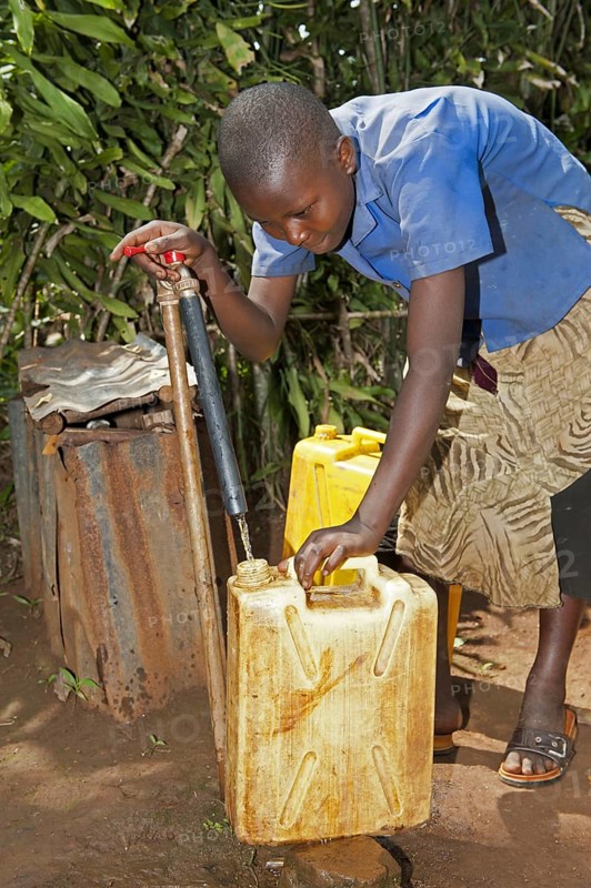Rwandan girl fills container with fresh water from a tap
