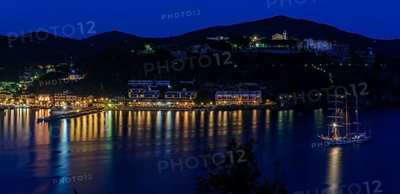 Panoramic view of Porto Azzurro with illuminated harbour promenade in evening mood during blue hour