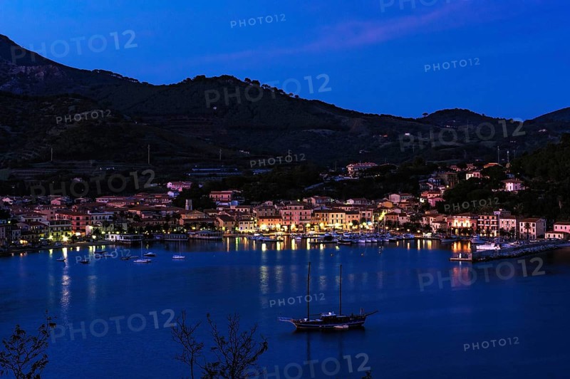 View of Porto Azzurro with illuminated harbour promenade in evening mood during blue hour