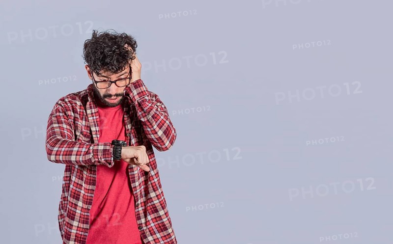 Worried handsome man looking at the time on the watch. Worried people looking at their watch