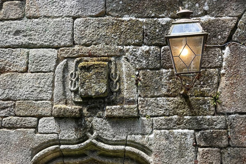 Coat of arms and streetlamp on the facade of an old stone house