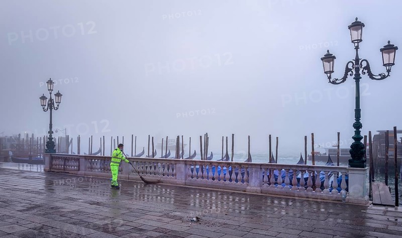 City cleaning staff in the morning fog at the gondola harbour in front of St. Mark's Square