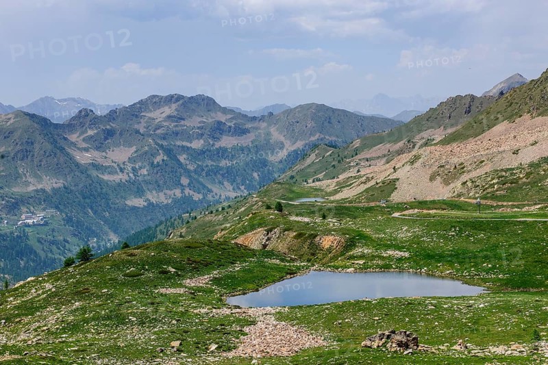 View of small mountain lake above tree line next to 2350 metre high Passo Lombarda pass at French-Italian border