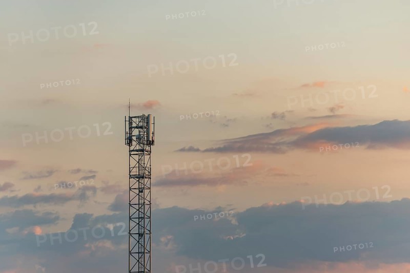 Telecom antenna in countryside in summer at sunset. Alsace