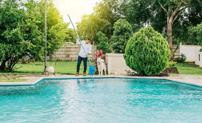 Man cleaning a swimming pool with skimmer