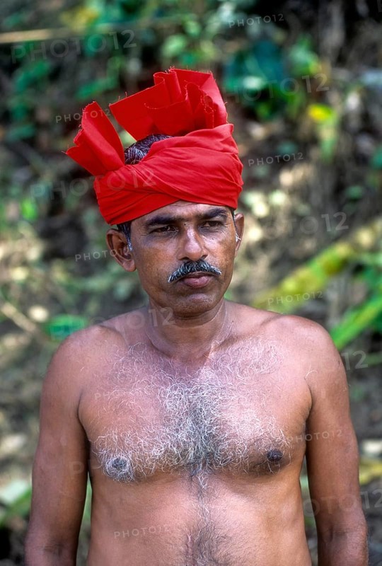 A shirtless man with red turban