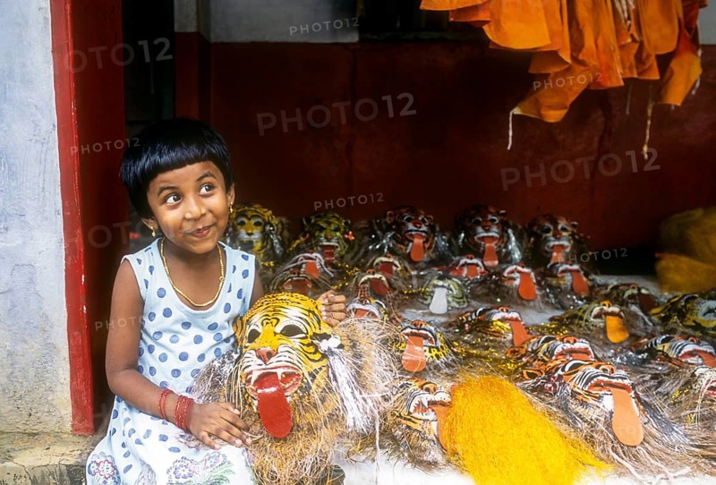 A girl child posing with pulikali mask in her hand in Thrissur or Trichur